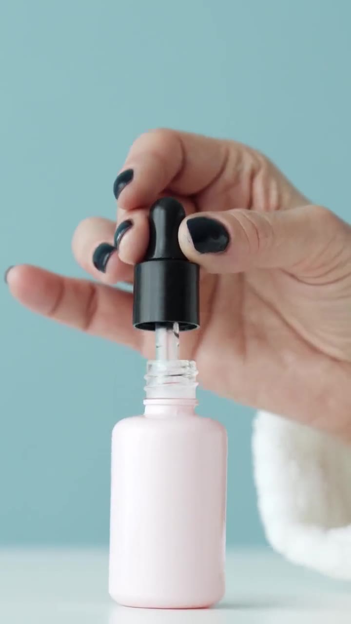 Conta-gotas pingando sérum num frasco rosa
