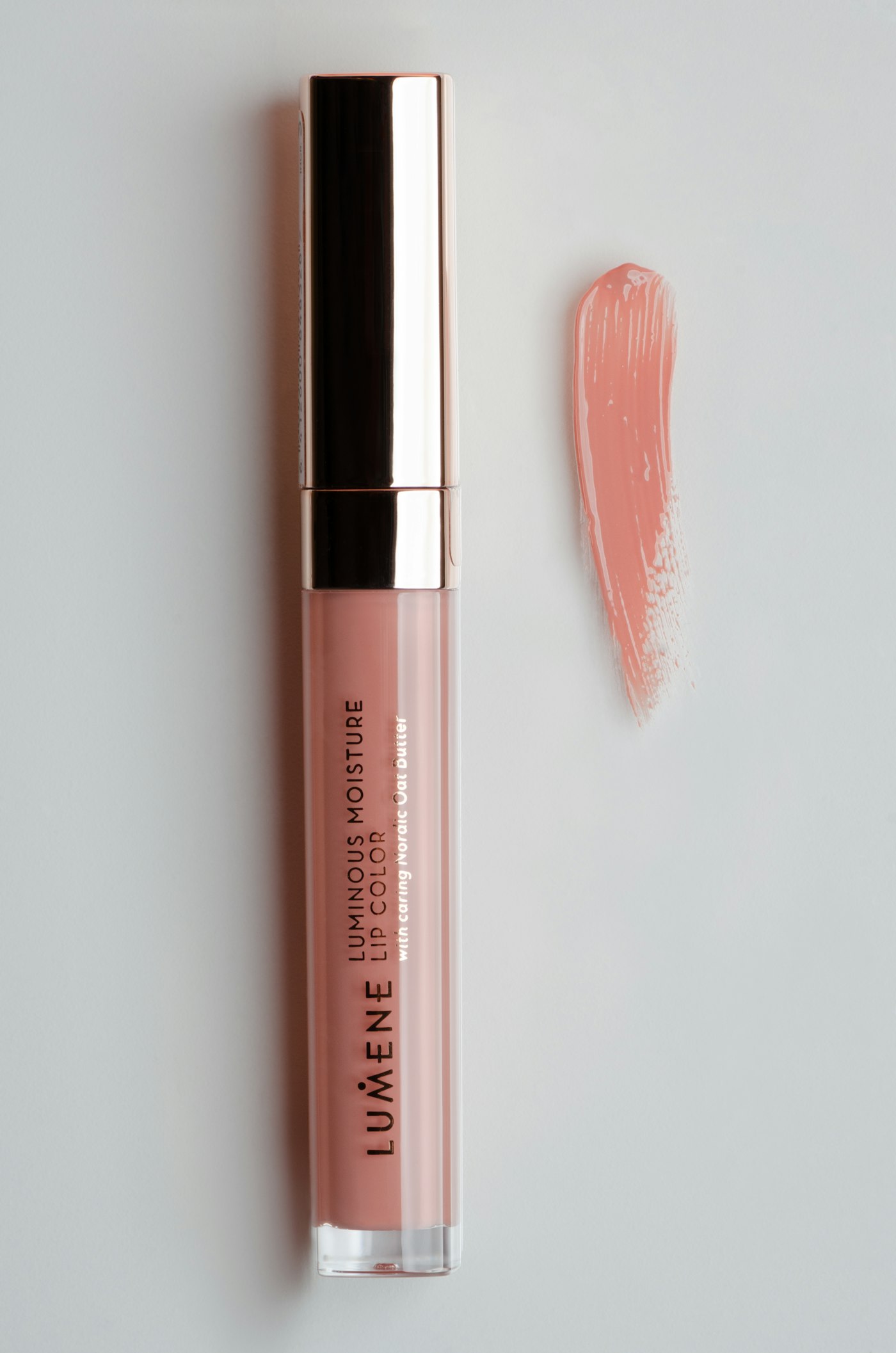Gloss labial rosa ao lado de um batom