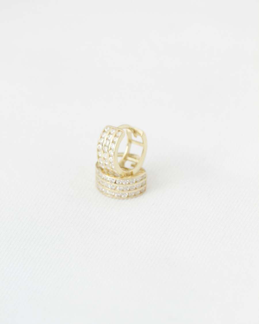 Argolas douradas com zircônias sobre fundo branco