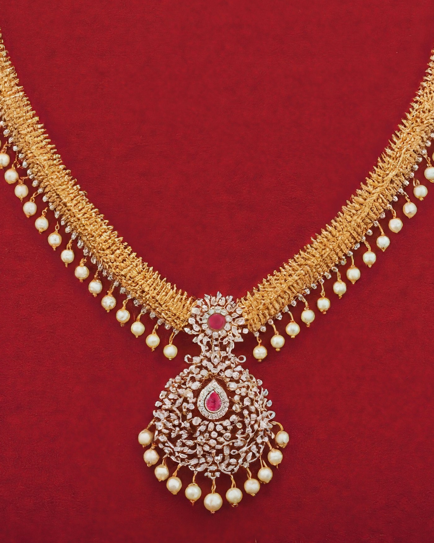 Colar dourado com pérolas sobre fundo vermelho