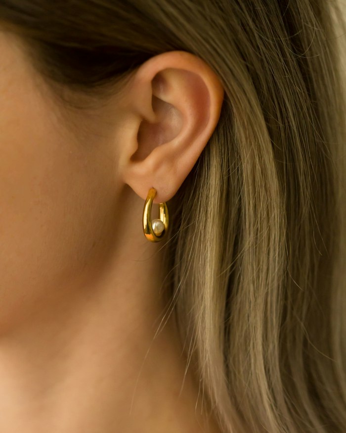 Close de orelha com brinco dourado